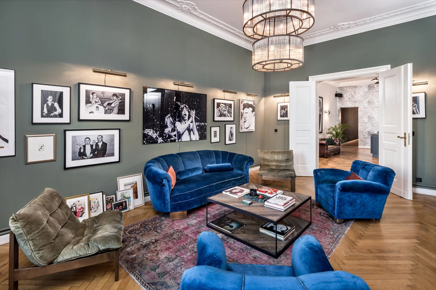 Blue velvet salon with a gallery wall and glass chandelier