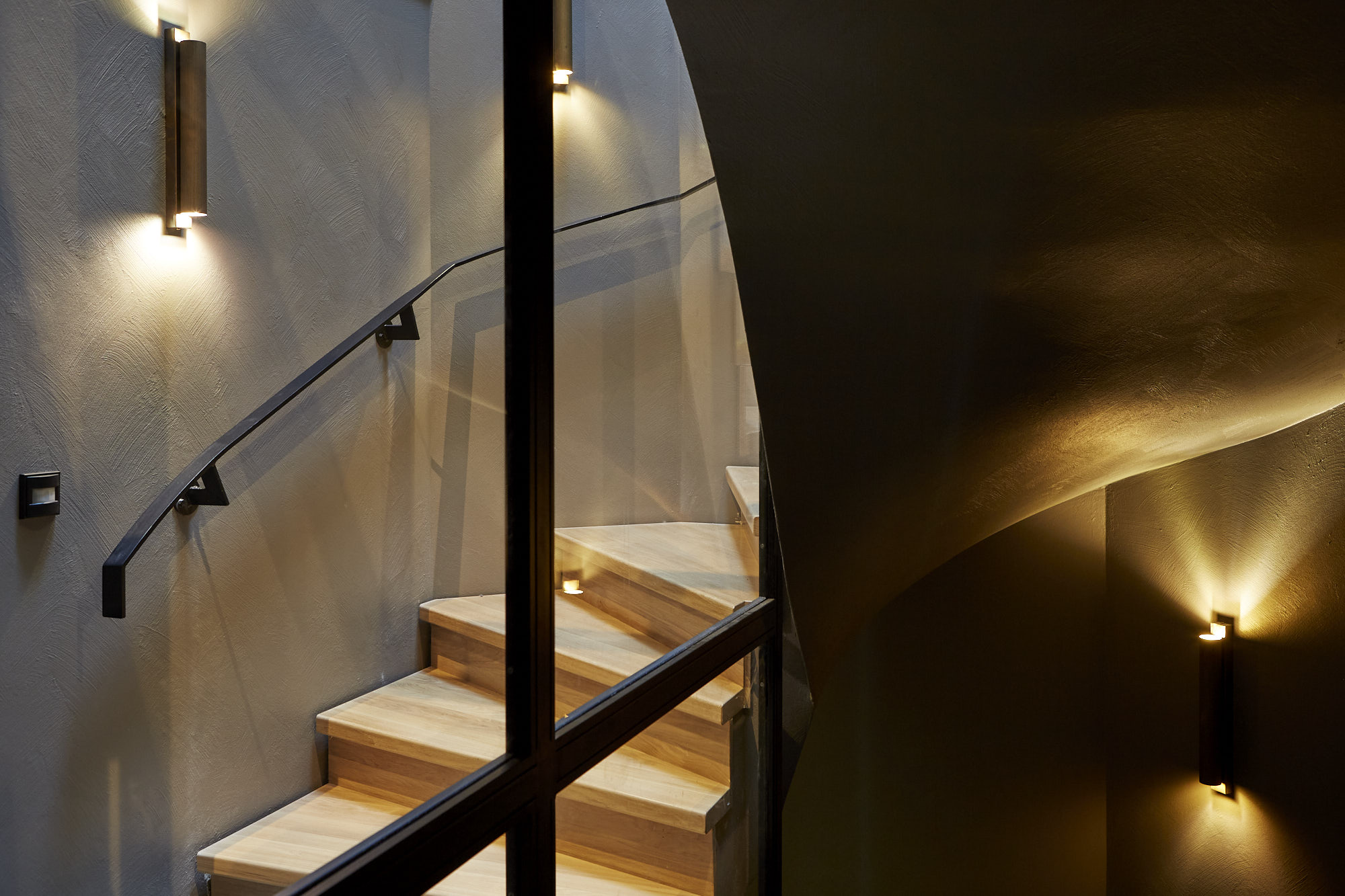 Oak staircase beside a curved plaster wall