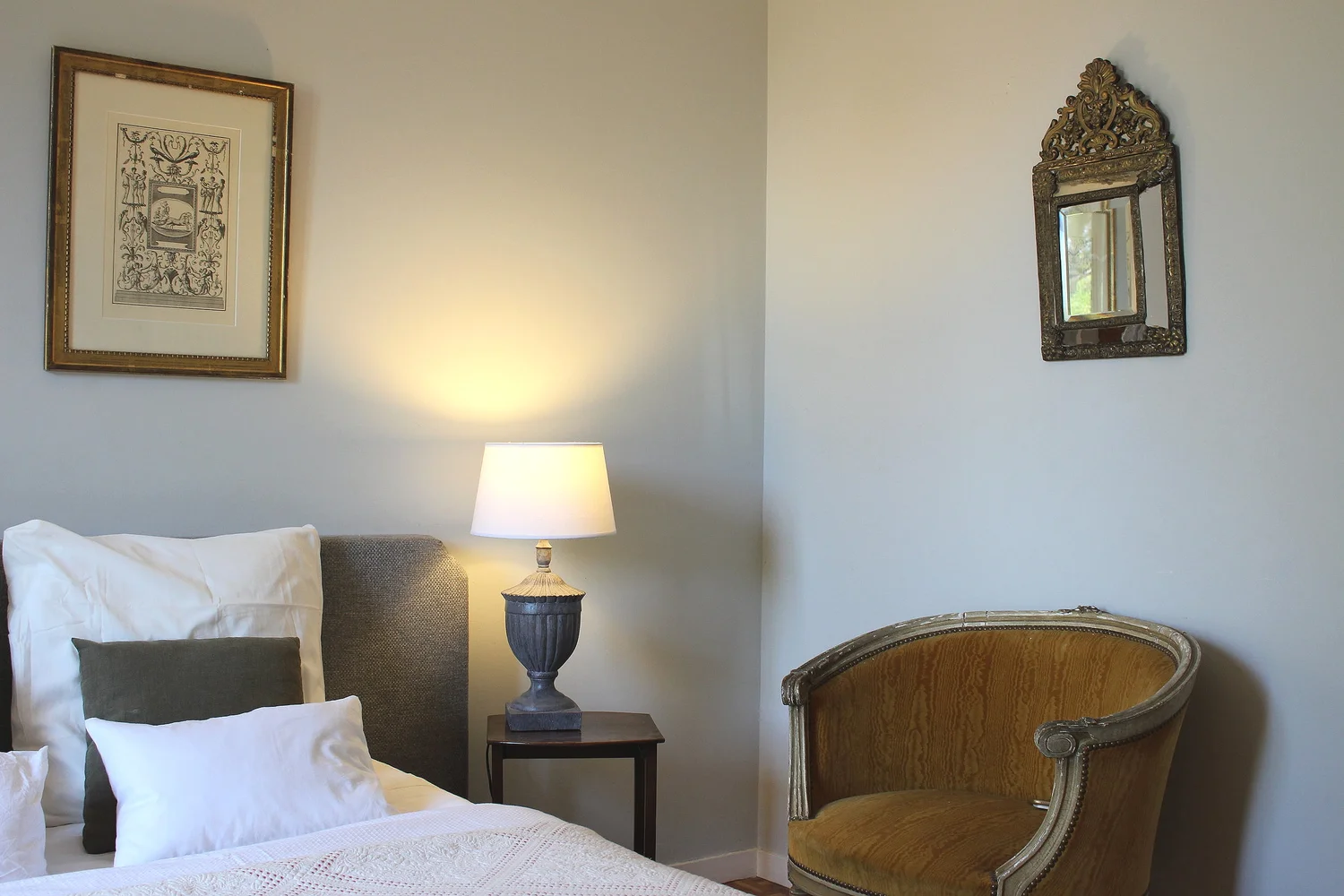Bedroom corner with a mustard armchair and a gilt mirror