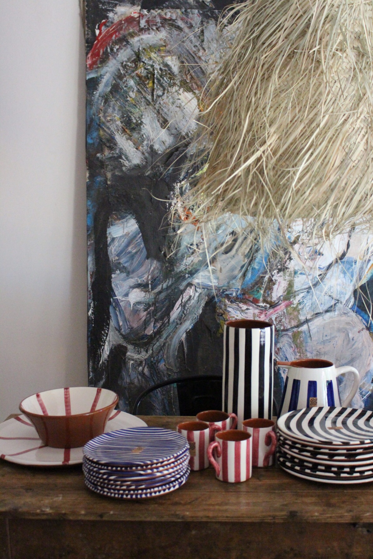 Hand-painted striped ceramics in front of an abstract painting